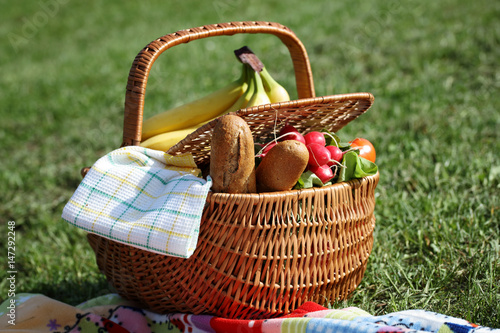 Picnic basket with healthy food and blanket on green grass in park, nature. Lunch break outdoors . Relax, Leisure Lifestyle Concept