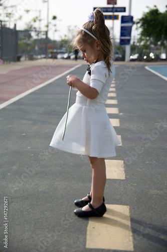 sad little girl in white dress on the road in park