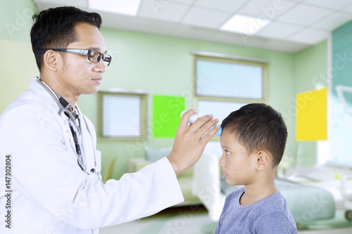 Pediatrician examining his patient temperature