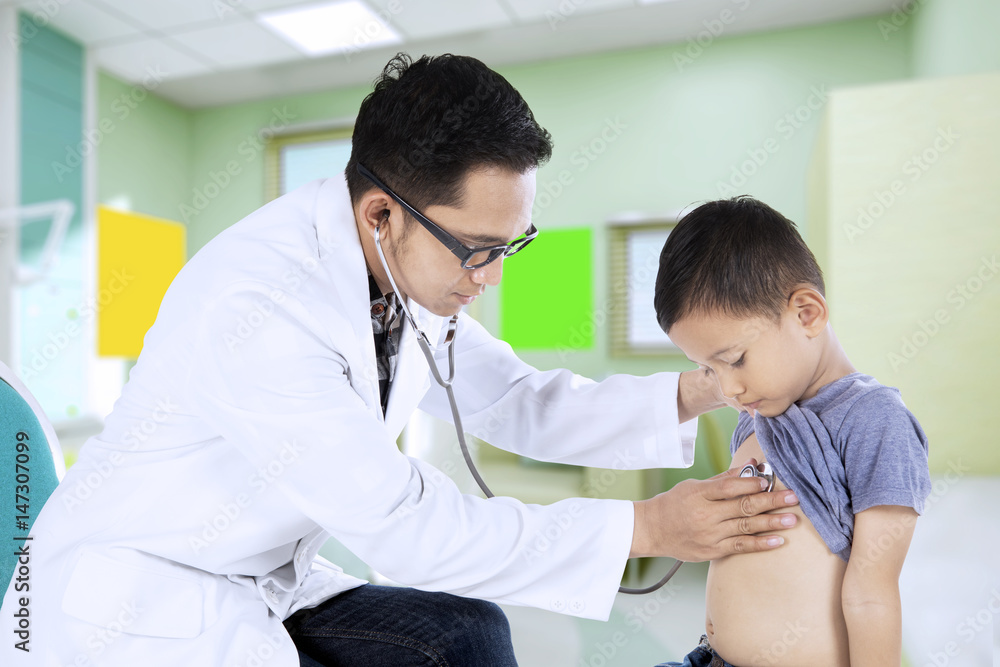 Young pediatrician examining little boy