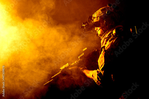 Security forces operator in Combat Uniforms with rifle, in the face of danger. Facing enemy, he is ready to fight. Studio contour silhouette shot, toned and colorized, backlight, profile side view