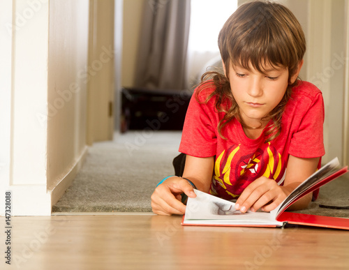 indoor portrait of young boy reading a book at home