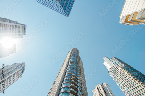 Apartment towers seen from below with blue sky and sunlight