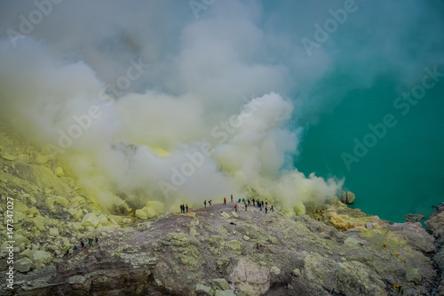 KAWEH IJEN, INDONESIA: Tourist hikers with backpacks and facial masks seen overlooking sulfur mine and volcanic crater