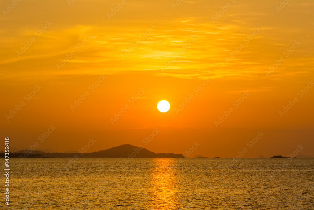 beautiful sky and cloud with orange sunset and silhouette mountain reflecting glows in sea surface