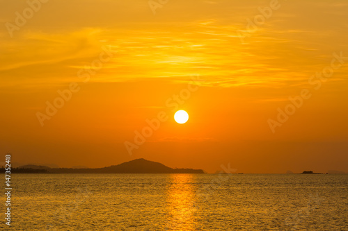 beautiful sky and cloud with orange sunset and silhouette mountain reflecting glows in sea surface