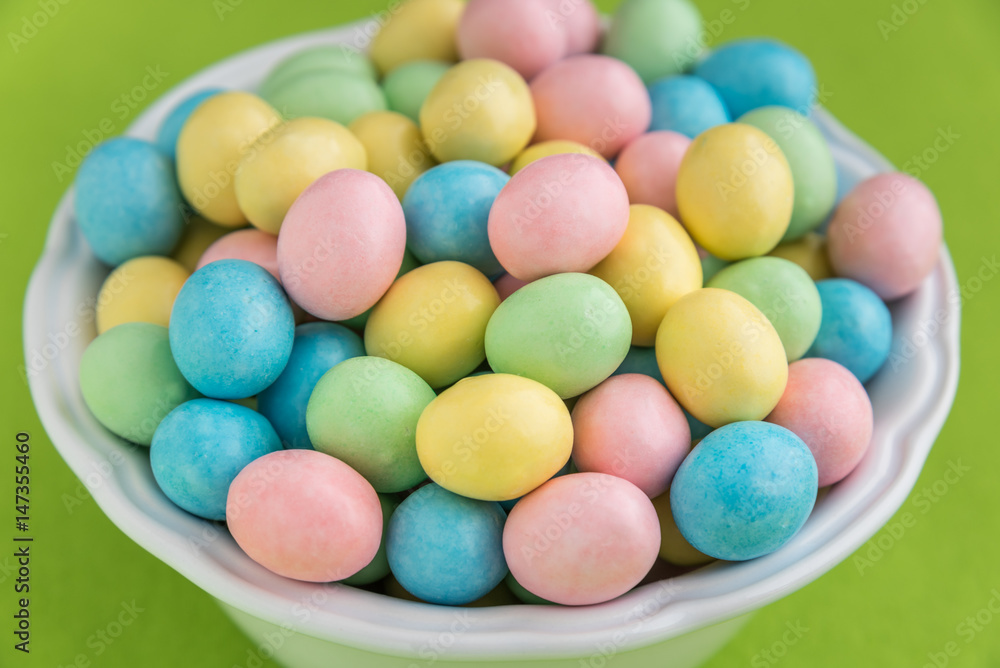 Bowl of pastel Easter candy eggs in a white bowl on a green background
Bowl of pastel Easter candy eggs in a white bowl on a green background