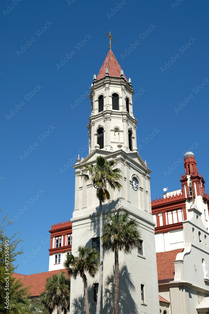 Bell tower and front entrance to the Cathedral Basilica of St. Augustine in St Augustine, Florida. Blue skies and palm trees.  Spanish Mission and Neoclassical architecture.  No clouds.