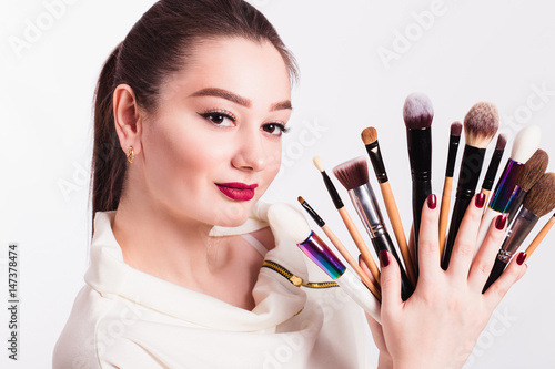 Makeup artist with brushes in hand on a white background