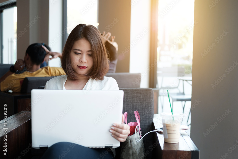 Businesswoman Working On Laptop In Coffee Shop. Young business woman uses laptop in cafe. Businesswoman working typing in a laptop Businesswoman Working On Laptop In Coffee Shop. Young business woman uses laptop in cafe. Businesswoman working typing in a laptop