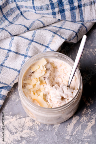 Healthy breakfast overnight oats with cocos and banana in a glass jar