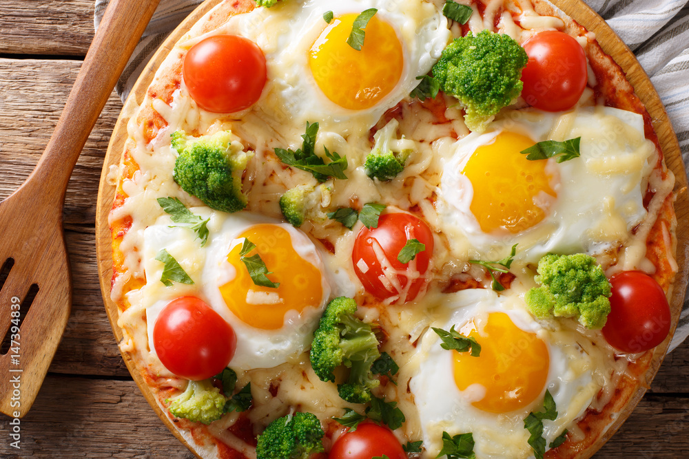 hearty breakfast of pizza with eggs, broccoli, tomatoes closeup on the table. horizontal top view