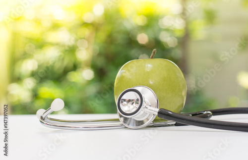 green apple with stethoscope with green background, Fruit is good for health concept