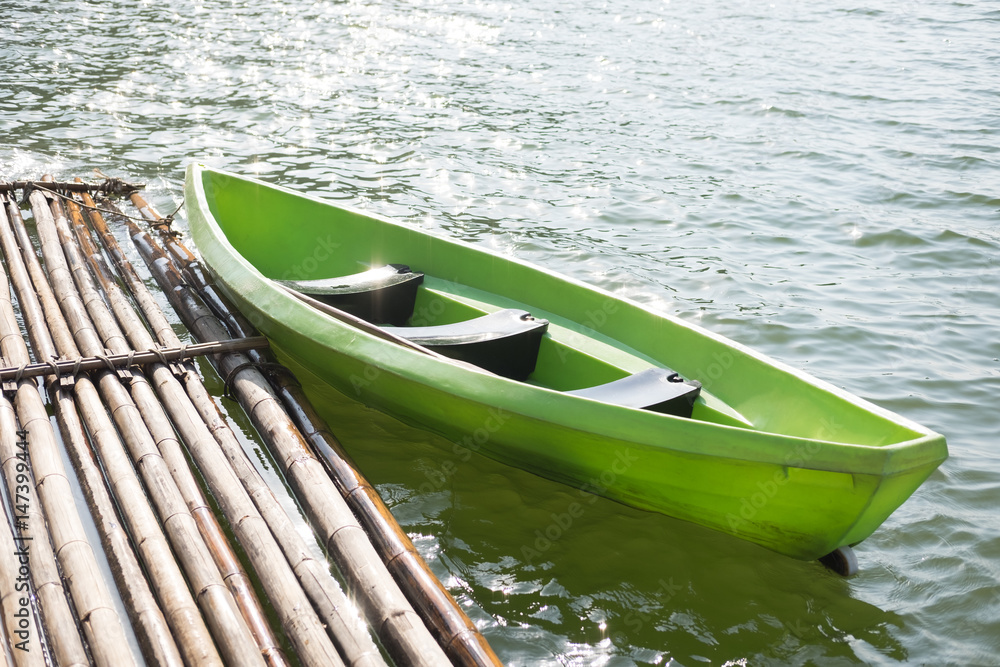 green plastic boat parked at bamboo raft on water surface. this image