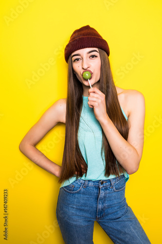hipster girl bite lollipop on yellow background
