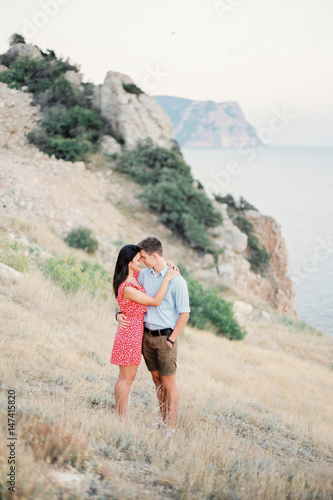 Young Stylish Couple in Love Walking in Mountains by the Sea. Vine Sunset Summer Mood