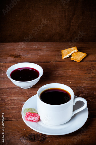 Cup of tea with jam  biscuits and marmalade on old wooden table against the background of burlap. Selective focus. Shallow depth of field. Toned