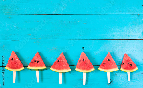 the summer watermelon slice popsicles on a blue rustic wood background. copy space for designer