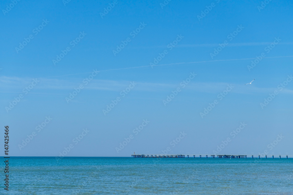 Pier in the black sea in the distance on the background of blue clear Sunny sky Pier in the black sea in the distance on the background of blue clear Sunny sky
