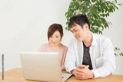 笑顔でノートパソコンを操作する男女   © buritora