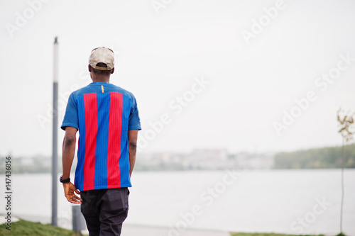 Back of walking stylish african american boy wear at cap, football t-shirt. Black sports man portrait. © AS Photo Family