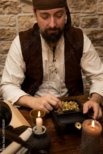Pirat mit Beute, Tisch mit Goldschatz, Kerzen und antiken Dingen