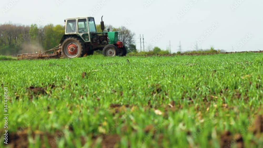 Agricultural tractor sowing and cultivating field, spring day Agricultural tractor sowing and cultivating field, spring day