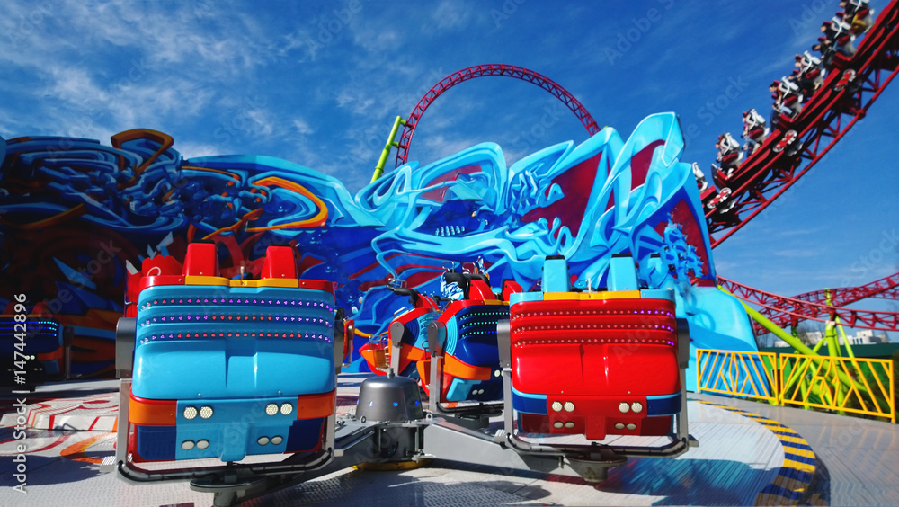 Bright booths on one of the rides in the amusement Park. Roller coaster in the background