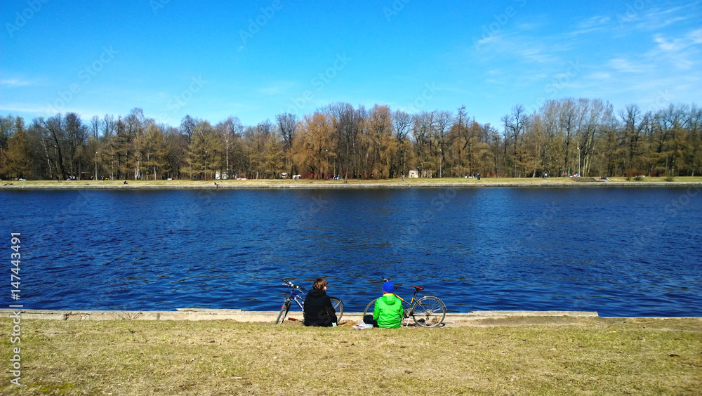 Obraz premium Mother and son are resting on the shore after Cycling. A cool spring day