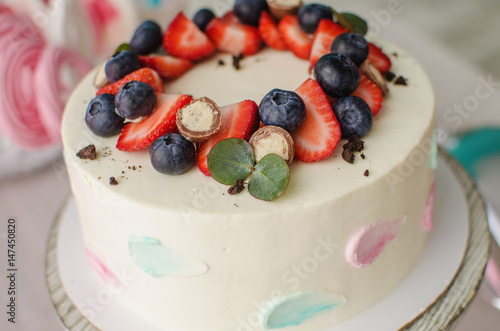 Delicious cream cake with chocolate balls decorated with strawberries and blueberries photo