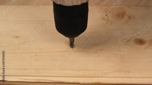 Someone is screwing a screw into wooden surface with the screwdriver. DIY concept