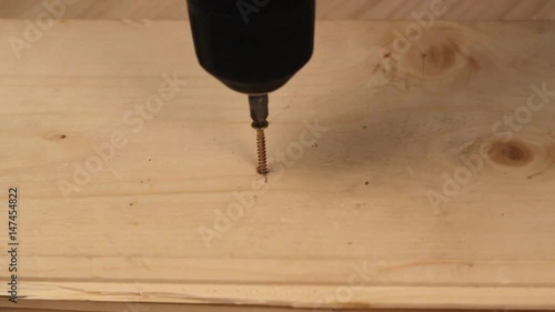Someone is screwing a screw into wooden surface with the screwdriver. DIY concept