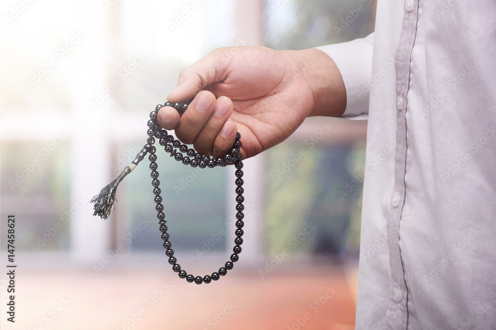 Hand of muslim man praying while holding tasbih Hand of muslim man praying while holding tasbih