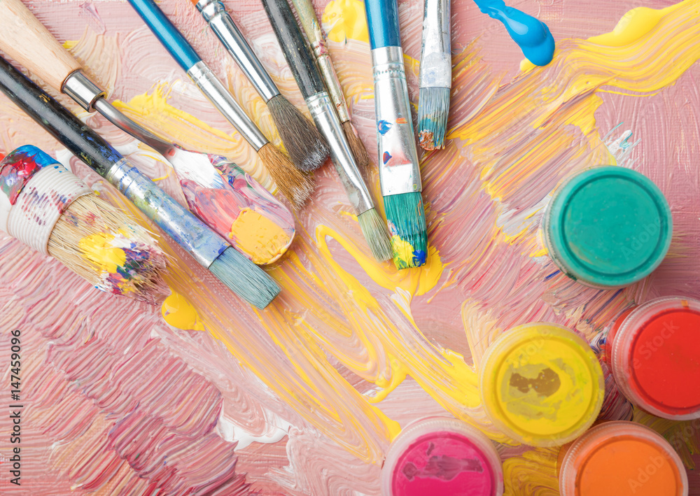 Fototapeta premium Artist paint brushes and color containers on colorful background