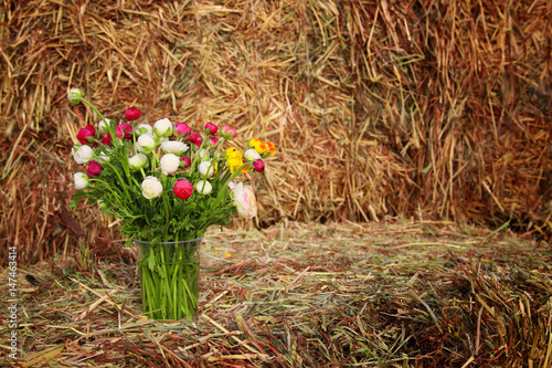 Fotografija beautiful spring bouquet of flowers on dry wheat haystack