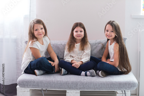 Portrait of three happy girls sitting on sofa and friendship concept