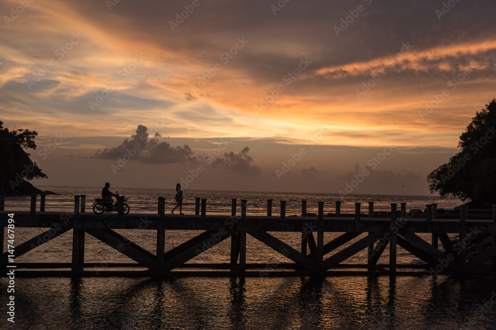 siluate picture motorcycle and women walking on  the bridge when sunset time, filling sad or alone