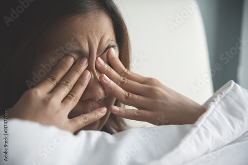 Asian woman rubbing eyes with her hands on her bed. Copy space. photo