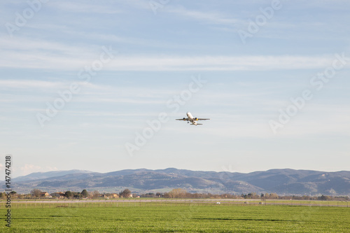 An airplane taking off from a little airport  with a big sky and green meadows
