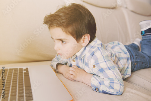 Little boy surfing on his laptop