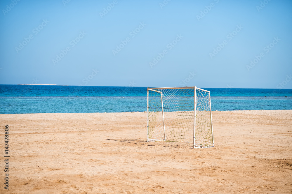 sea shore with soccer gate with net on sand