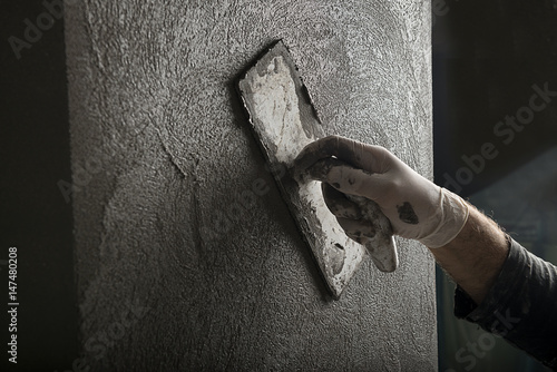 Hand of a construction worker plastering and smoothing concrete wall close-up. photo