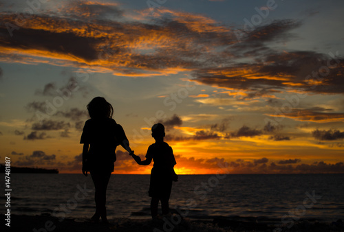 Mom and son at sunset by the ocean.