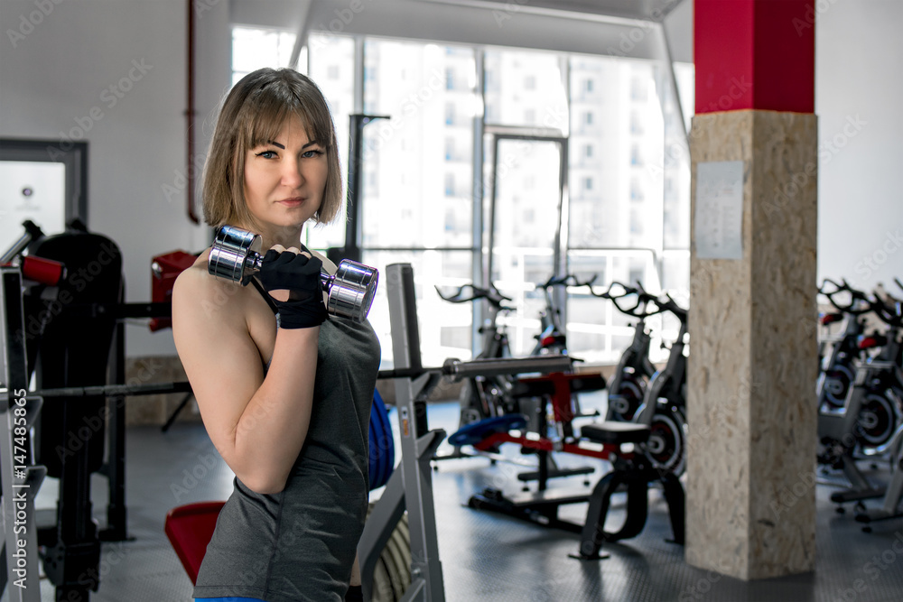 Strong girl athlete with dumbbells trains in the gym Strong girl athlete with dumbbells trains in the gym