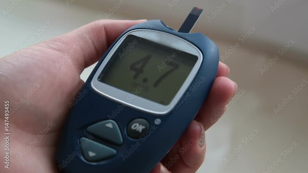 Close-up shot of woman hand holding glucometer with normal blood sugar range Close-up shot of woman hand holding glucometer with normal blood sugar range