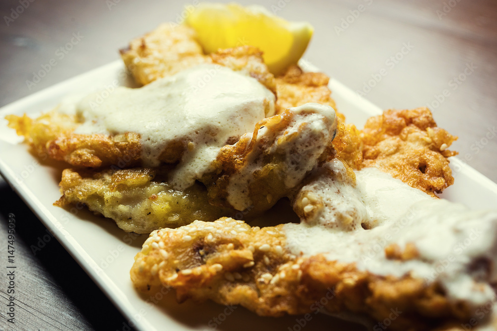 Fish fried in batter,Delicious battered fish on a plate with chips,Fish and chips meal.Battered cod with fries. Fish fried in batter,Delicious battered fish on a plate with chips,Fish and chips meal.Battered cod with fries.