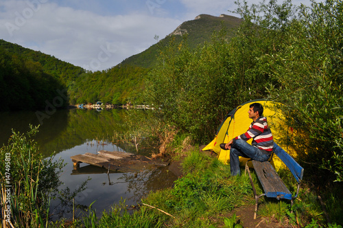 Young man camping by the river and get rest in nature. Morning on the river