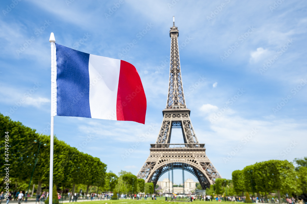 French flag flying in bright blue sky above the Eiffel Tower in Paris, France - obrazy, fototapety, plakaty 