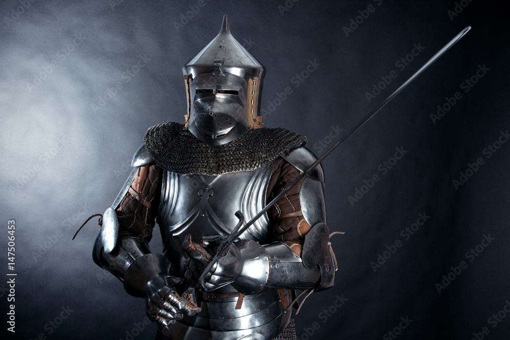 A medieval warrior in a helmet and with a sword. Knight on dark background A medieval warrior in a helmet and with a sword. Knight on dark background