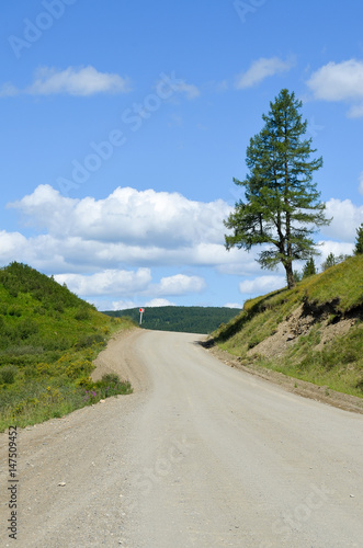 A dirt road with a blue sky and clouds.